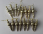 Flat lay of all 16 champagne gold Christmas spindle baubles in matte and glittered finishes arranged in two rows with ribbed spherical tops, twisted middles and elongated pointed drop bases with gold hanging strings on a plain light grey background