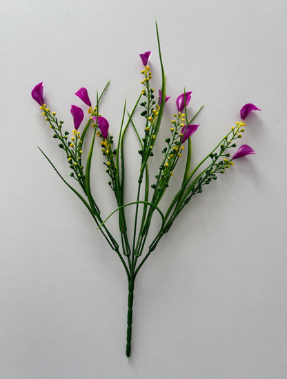 Upright full spread shot of an artificial pink small calla lily foliage bunch showing five individual wired stems fanning out from a single bottom stem with small bright magenta pink calla lily flower heads, tall thin green grass stems and small bright yellow berry pick stems all arranged against a plain light grey background