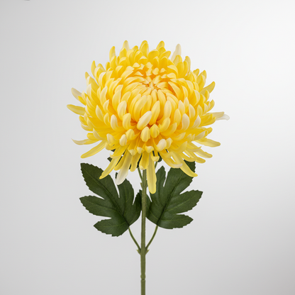 Full length view of a single artificial yellow chrysanthemum stem showing the complete wired green stem with dark green detachable leaves and a large yellow mop-head bloom on a plain light grey background