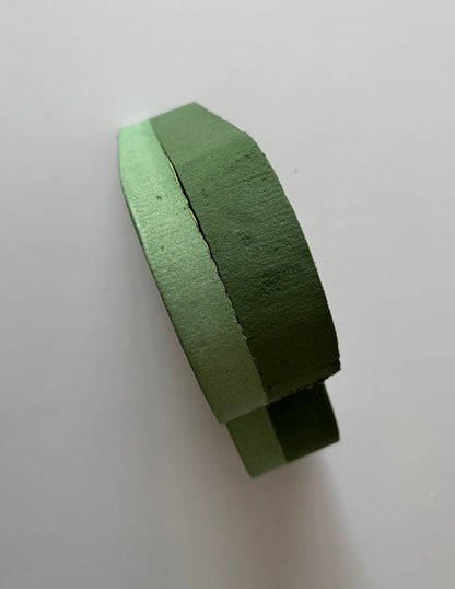 Upright standing shot of a green heart shaped oasis wet floral foam frame balanced on its base edge showing the full 6cm depth and thick two layer foam construction from the side clearly against a plain off white background