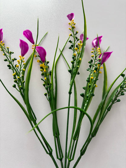 Upright portrait shot of an artificial pink small calla lily foliage bunch from a slightly wider angle showing the full stem length with five individual wired stems clearly separating from a single bottom stem with small bright magenta pink calla lily flower heads, tall thin green grass stems and small bright yellow berry pick stems against a plain light background