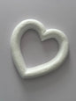 Overhead flat lay shot of a white polystyrene heart wreath frame 28cm showing the full hollow heart ring shape with thick textured polystyrene border against a plain neutral grey background